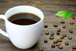 Mug of coffee cup of coffee and coffee beans on table