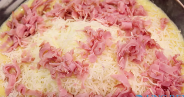 Chopped ham being added to egg mixture in bowl.