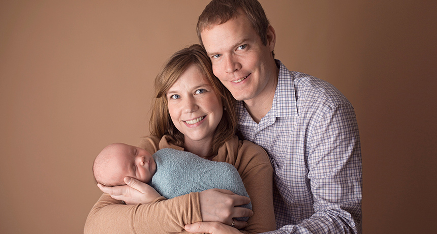 A man and woman together, both holding their infant.