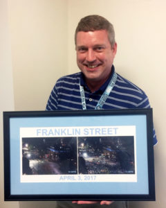 Paul Fowler with the 2017 Franklin Street poster showing empty street and Franklin street after UNC win.
