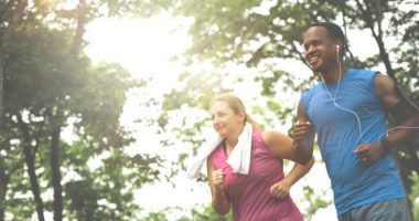 a couple running together on a sunny day, under trees