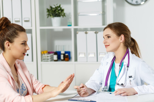 Female patient talks to female provider, sitting at a conference table