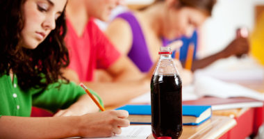 a girl iin school with a cola on her desk
