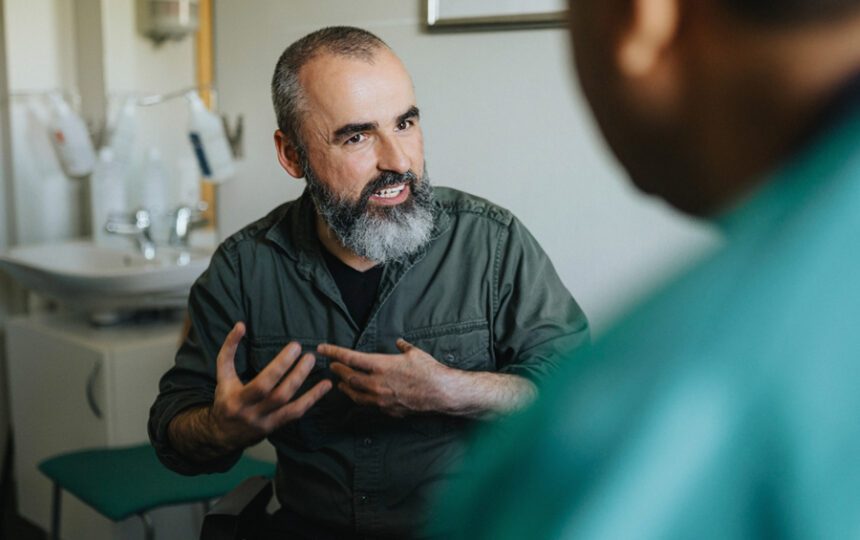 Man in middle age with graying beard talks to provider