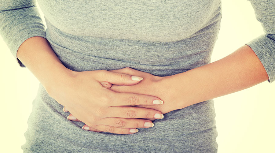 Mid-shot of woman clutching her abdomen