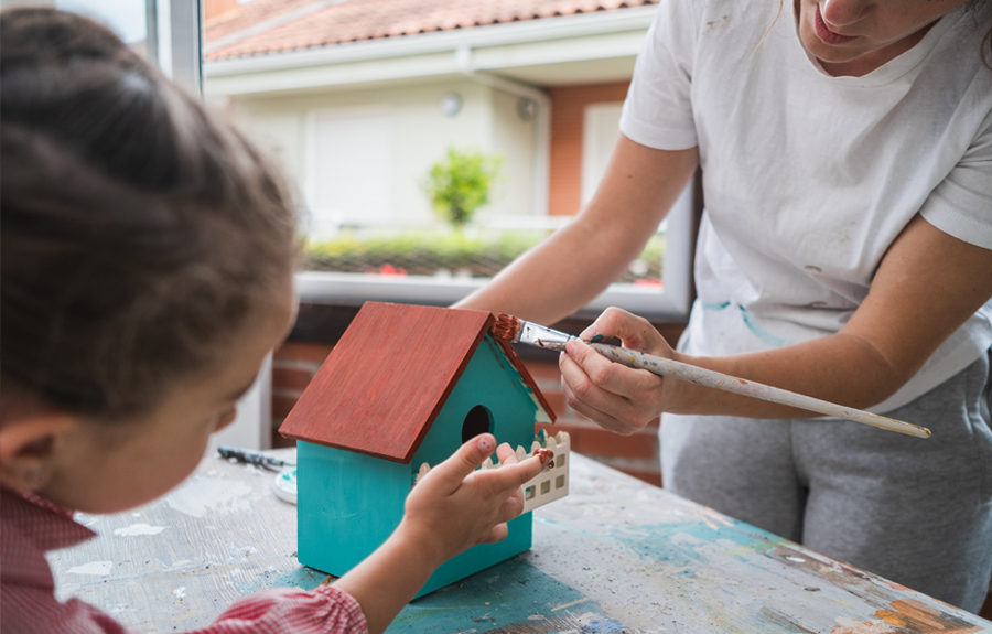 Mom and young daughter working on decorating a bird house together
