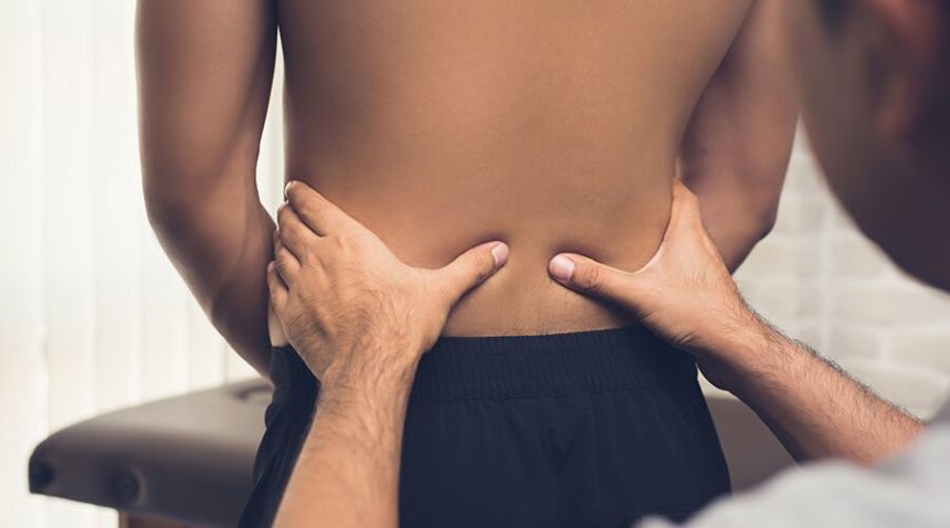 physician pressing on patient's lower back