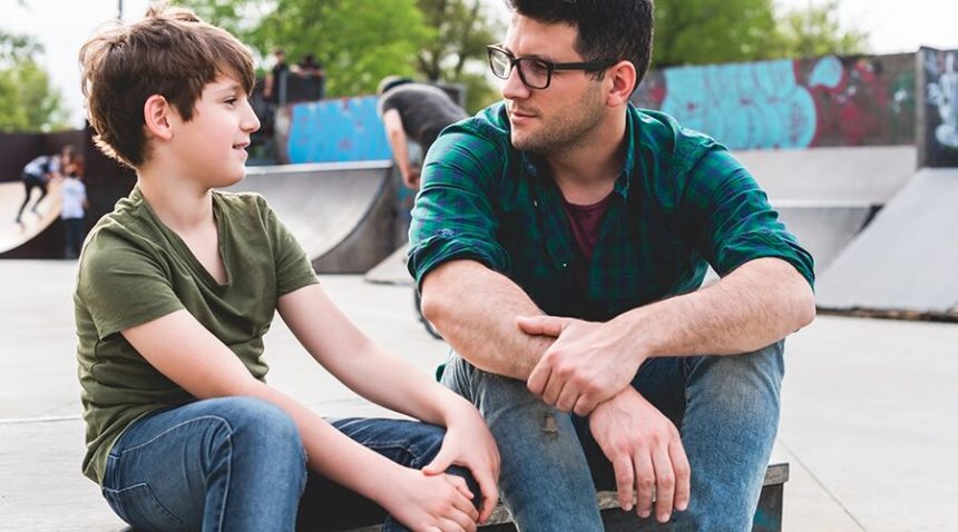 Older boy talking to younger boy at a skate park