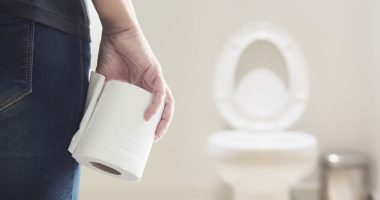 woman holding toilet paper in front of a toilet