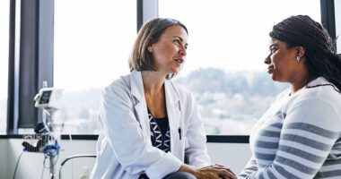 OB/GYN provider speaks to a female patient in a high-rise hospital room