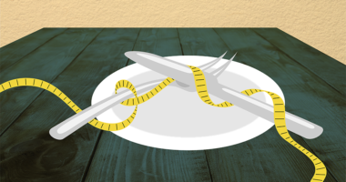 A plate with a knife and fork on it with a tape measure.