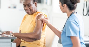 A healthcare professional administers a vaccine to an adult woman during a medical appointment.