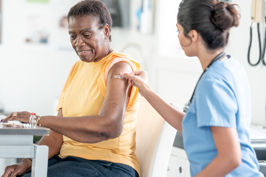 A healthcare professional administers a vaccine to an adult woman during a medical appointment.