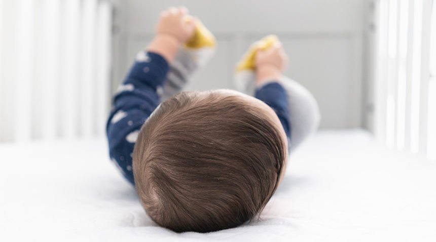 photo of top of an infant's head as he lies in a crib