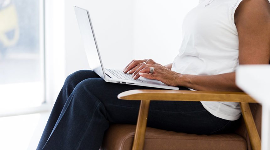 middle-aged woman sitting in chair, typing on computer