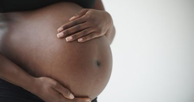 African-American woman holding pregnant belly