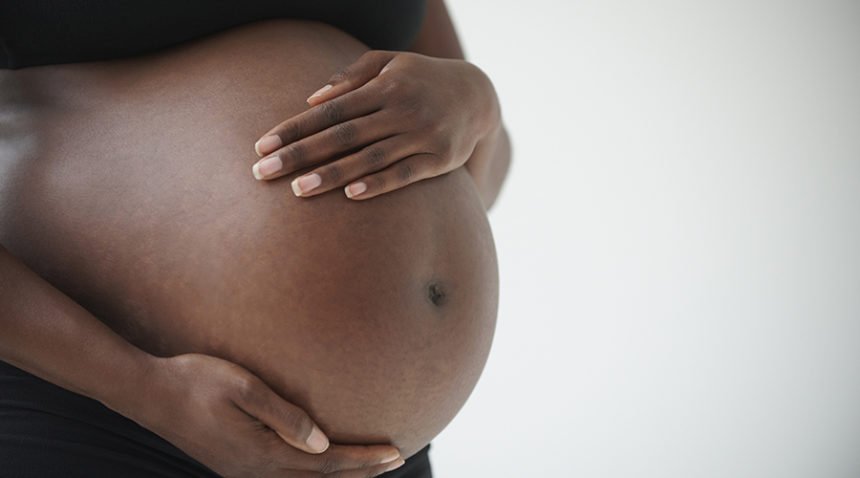 African-American woman holding pregnant belly