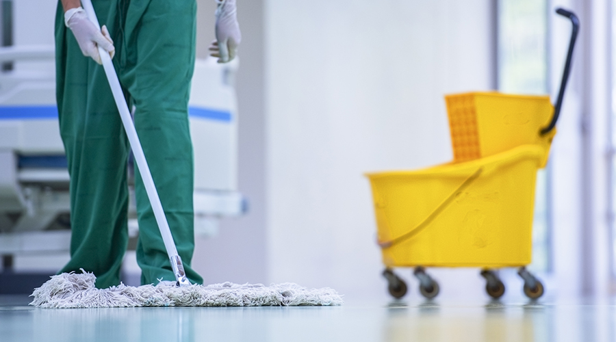 person wearing scrubs mops floor of hospital