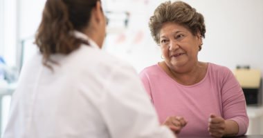older latina woman talking to provider in white lab coat