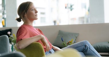 woman sitting on couch, looking into distance
