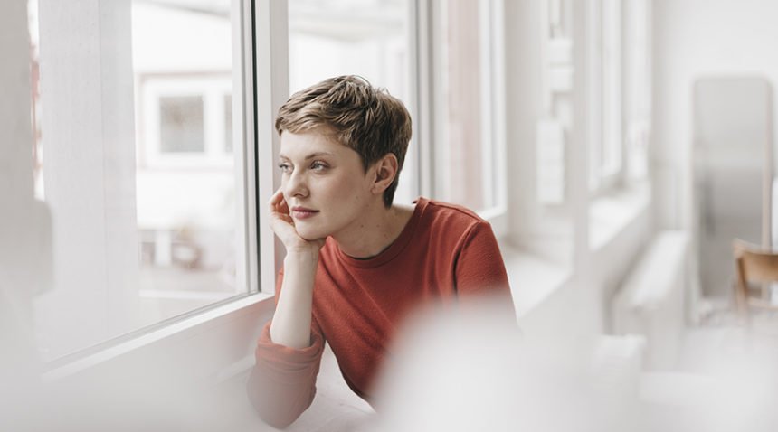 woman looks pensively out window