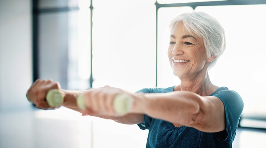 older woman lifts weights, smiling