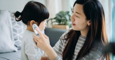 mom checks child's body temperature with an ear thermometer