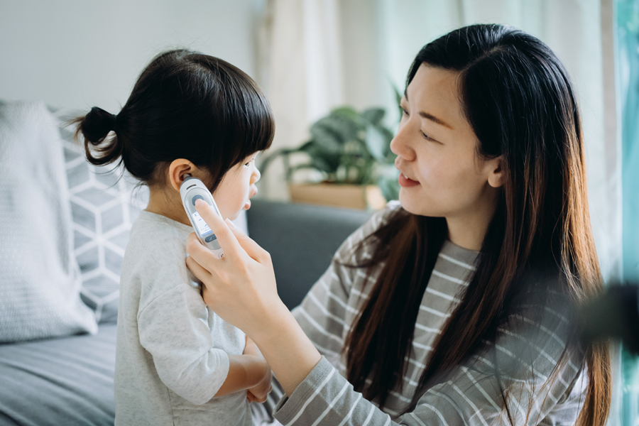 mom checks child's body temperature with an ear thermometer
