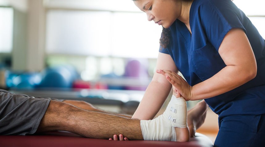 Sports medicine doctor works on patient's wrapped ankle