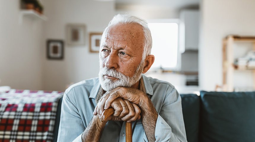 older man with white bead looks contemplatively to the side of the frame