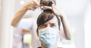 Adult Man Sitting in Hair Salon Wearing Protective Mask During COVID-19 Pandemic.