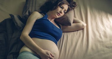 Pregnant woman feeling pain in her belly lying in bed with insomnia at night. The concept of pregnancy and health