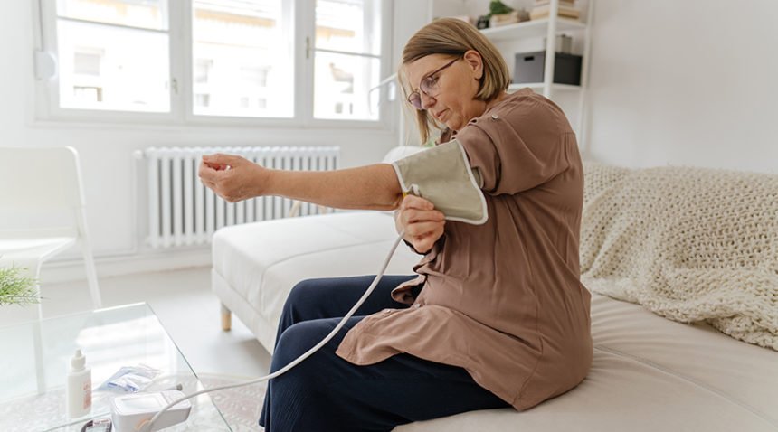 Photo of a senior woman checking her blood pressure level at home