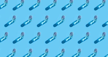 Coronavirus medical vaccine pattern. Covid-19 coronavirus vaccine liquid on glass bottle on pastel blue background. Copy space.