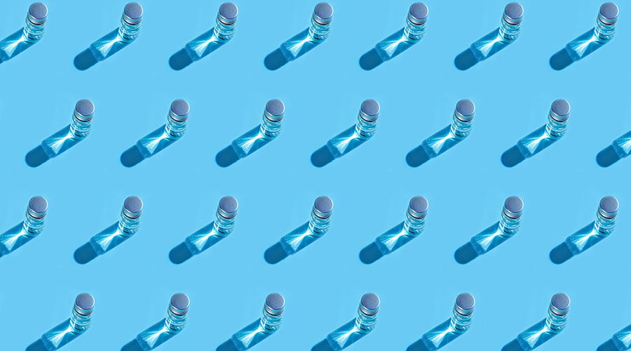 Coronavirus medical vaccine pattern. Covid-19 coronavirus vaccine liquid on glass bottle on pastel blue background. Copy space.