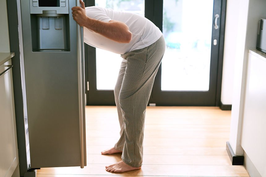 Shot of a man peering into the fridge at home