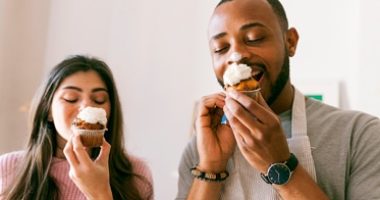 a young man and a young woman each eat a cupcake