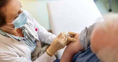 Top view of a Female doctor giving vaccine to a senior man in her clinic.