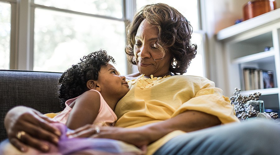 Grandmother and granddaughter cuddling on couch