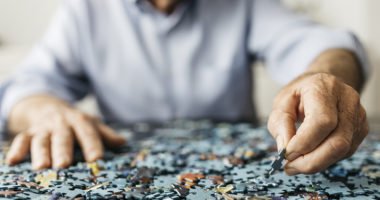 Senior retired man doing a puzzle, image focused only hands.