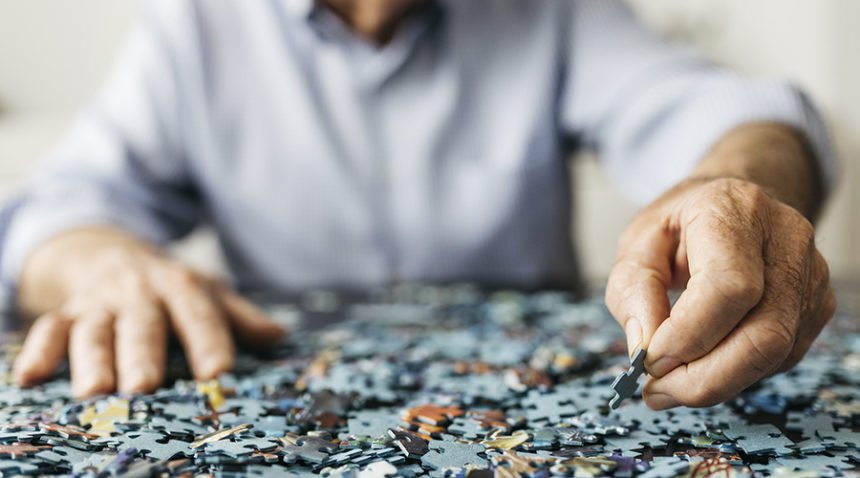 Senior retired man doing a puzzle, image focused only hands.