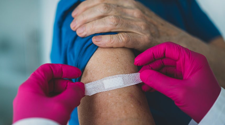 provider places bandage over the arm of someone just vaccinated