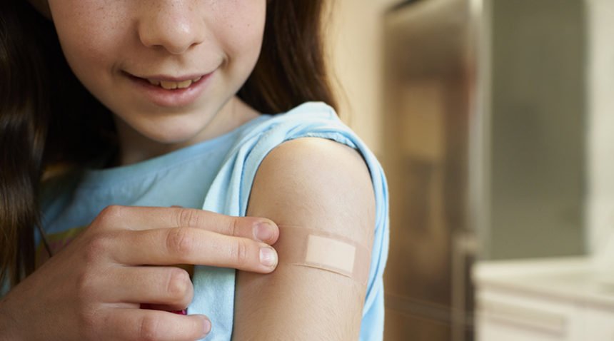 Girl showing her arm with a bandage after receiving the covid-19 vaccine.