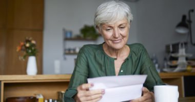 Senior woman reading letter while sitting at home