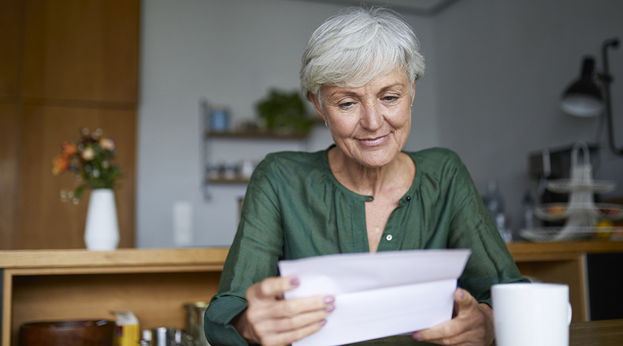 Senior woman reading letter while sitting at home