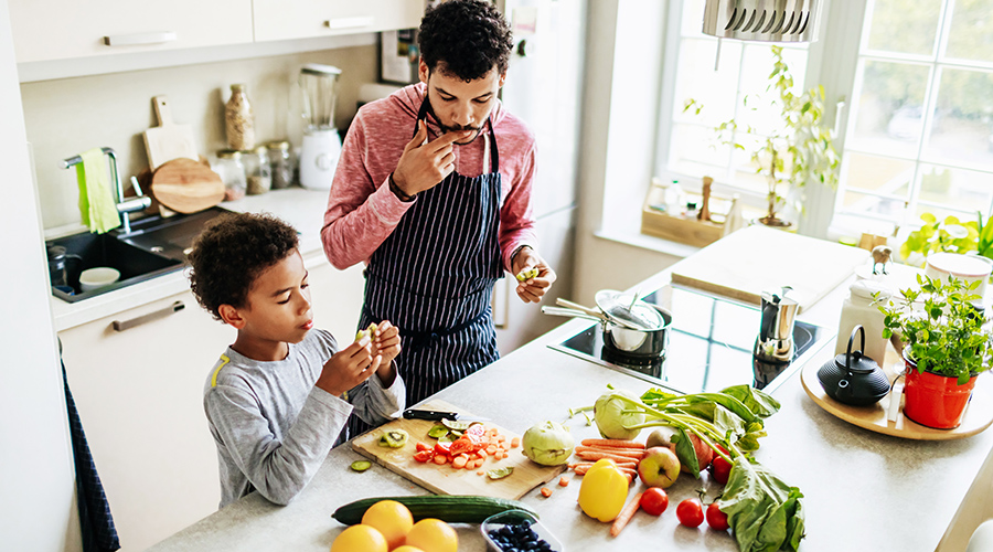 Dad spending some time with his son, snacking while they prepare some lunch together.