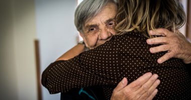Elderly man hugs adult daughter