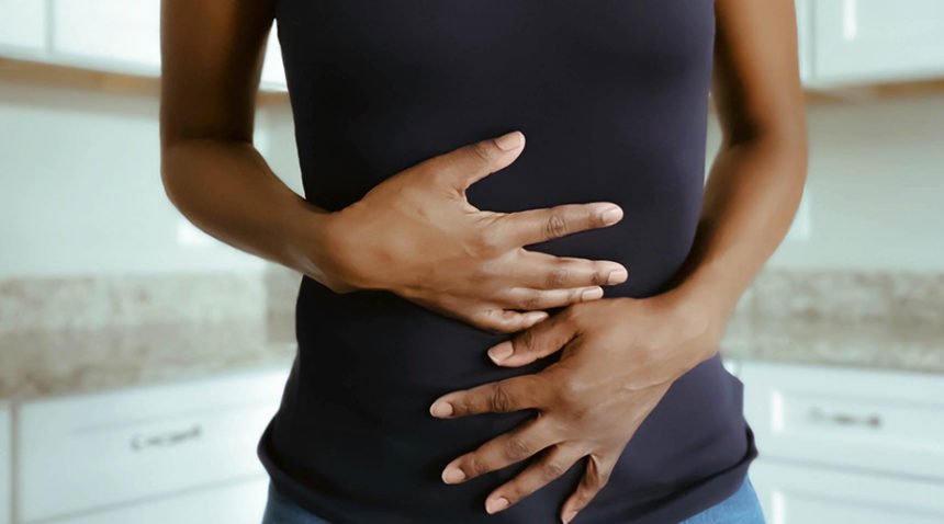 mid-shot of woman clutching her stomach in pain