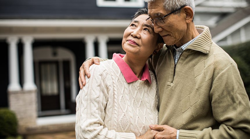 Senior couple embracing in front of home