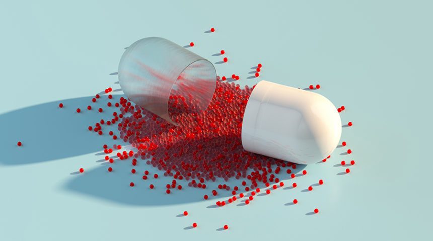 Digital generated image of abstract opened plastic capsule pill with small red spheres inside on pastel blue background.